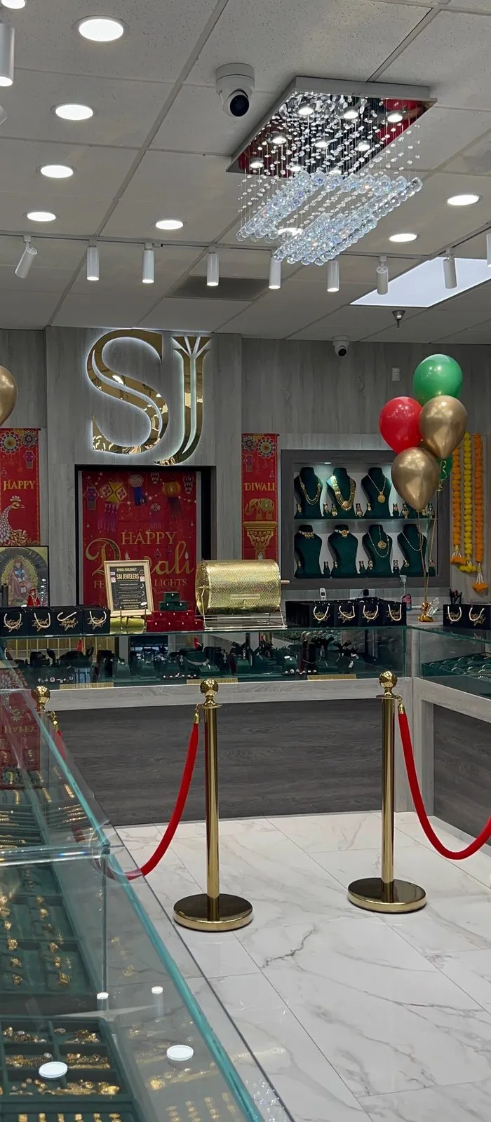 Inside the Sai Jewelers showroom in Modesto — the SJ emblem, crystal chandelier, and gold display cases decorated for Diwali