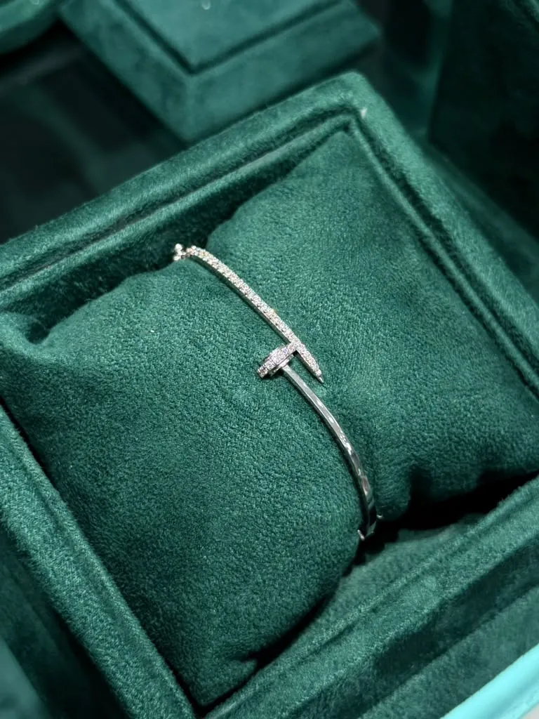 Pavé diamond nail-style bangle resting on an emerald velvet pillow