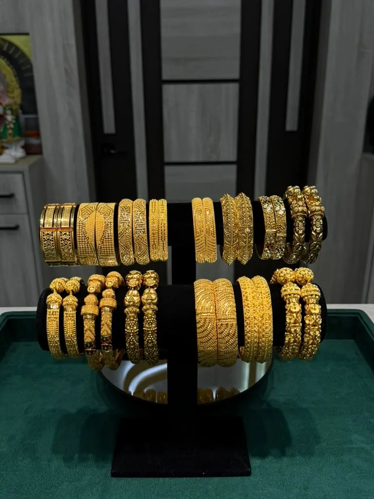 Two-tier display of 22K gold ladies bangles and kadas in varied patterns on black velvet stands