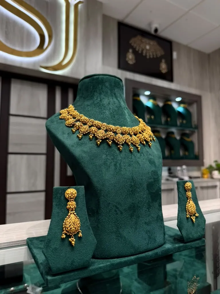 22K gold necklace with floral medallions and matching drop earrings on a velvet bust